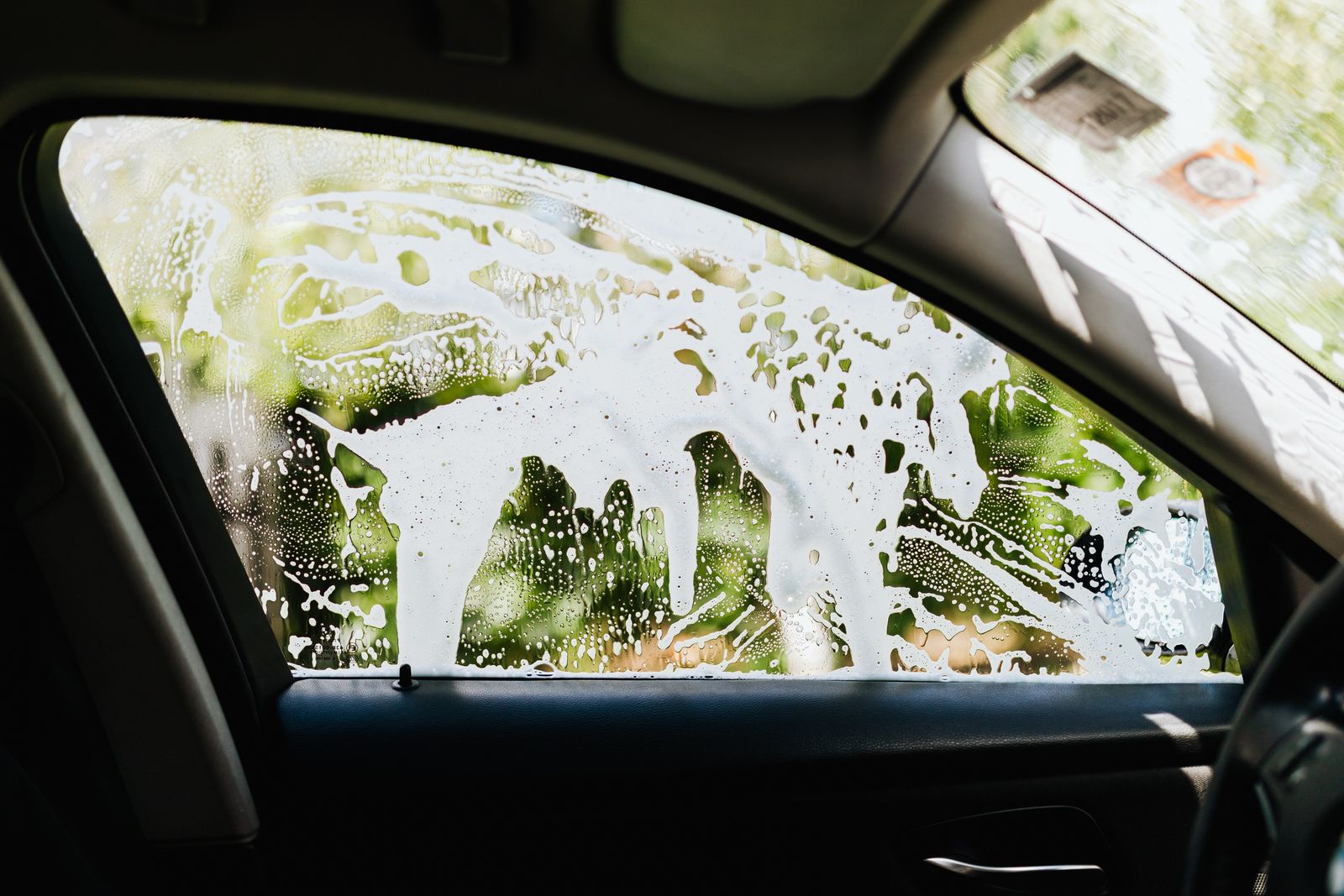 View from inside a car as soap covers the window in the wash