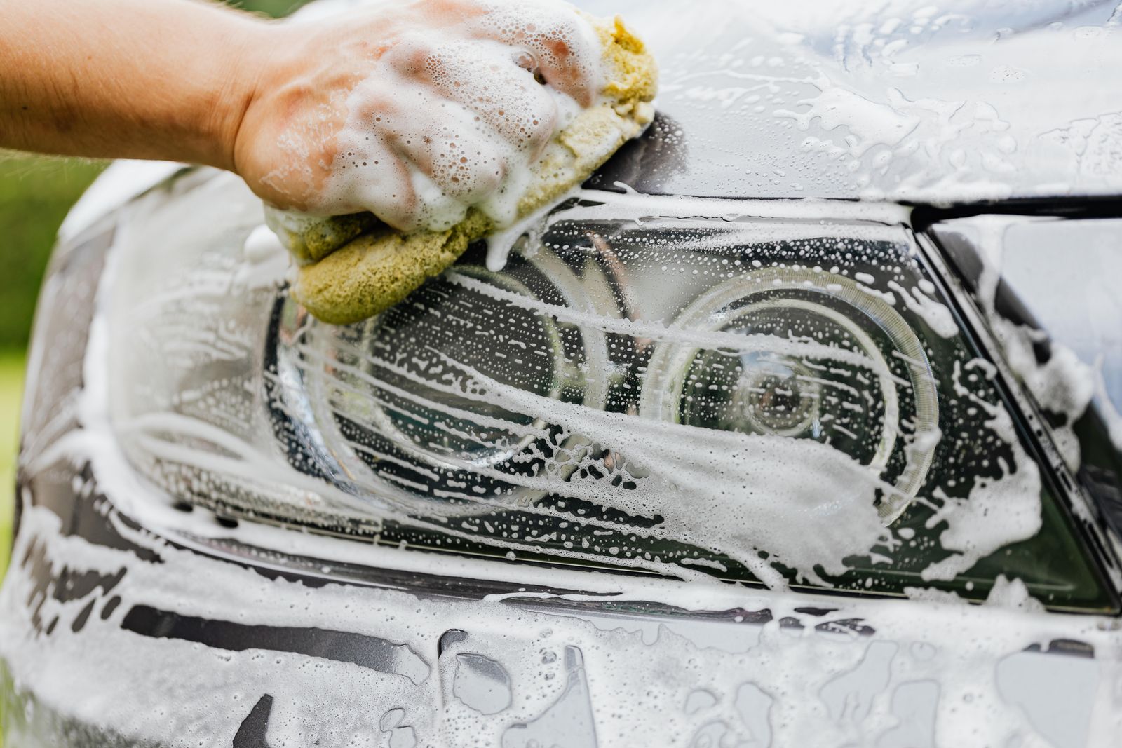 Hand scrubbing a cloudy headlight with a sponge