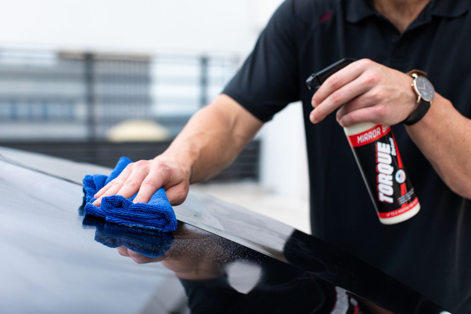 Hands buffing paint with a microfiber cloth and spray wax